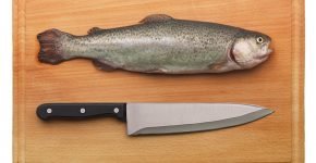 Рыба сырая на разделочной доске рядом с ножом